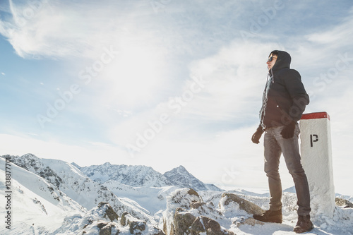 Portrait of a man in full growth on top of the snow-capped mountains.