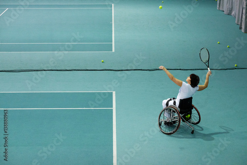 Schilderij op canvas Disabled mature woman on wheelchair playing tennis on tennis court