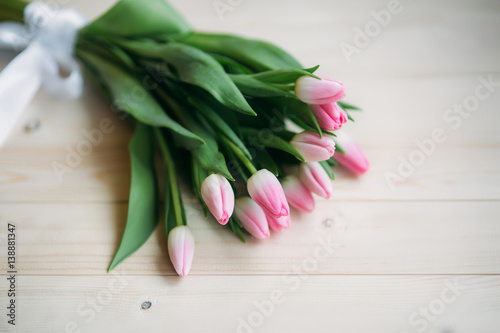 Pale pink tulips lie on a wooden table. Flowers as a gift.