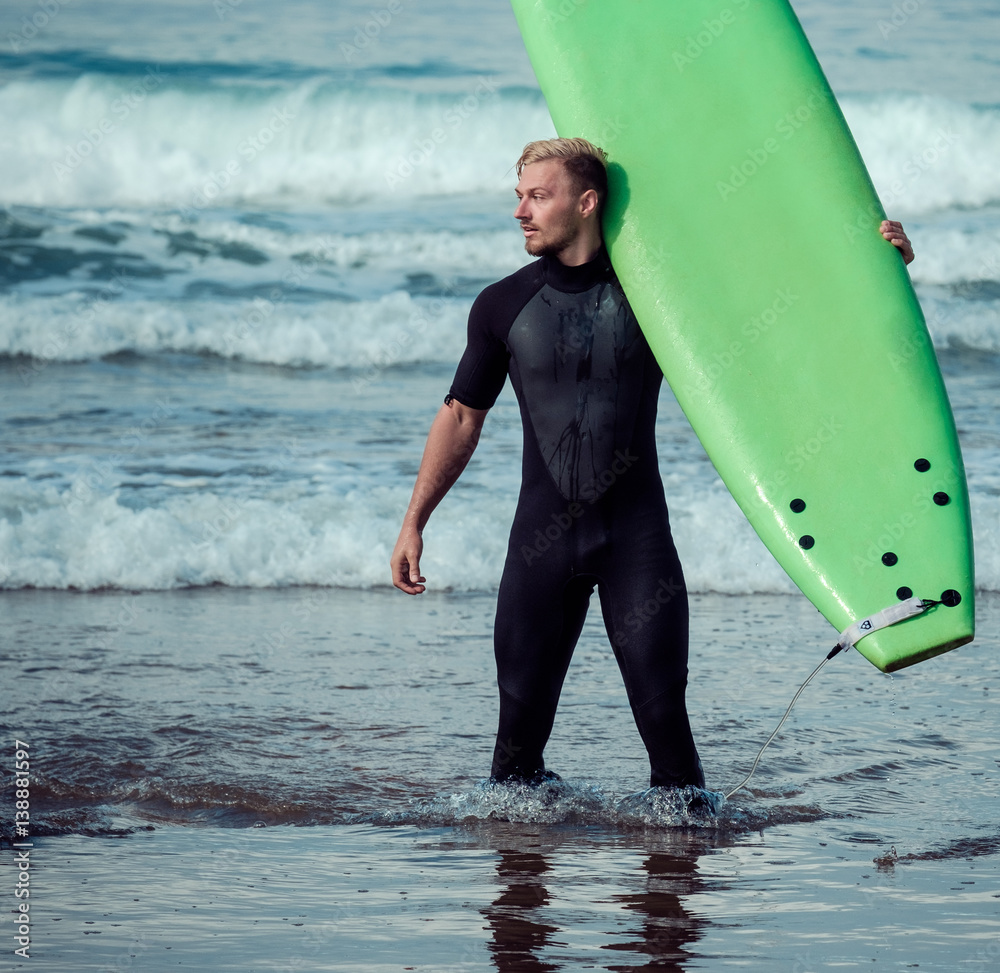 Surfer wearing wetsuit standing on the beach with a surfboard Stock ...