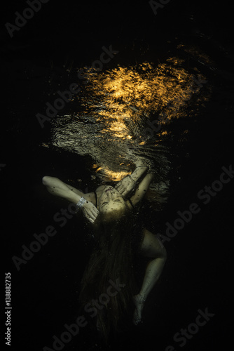 unconscious girl levitats underwater with fire over the surface
