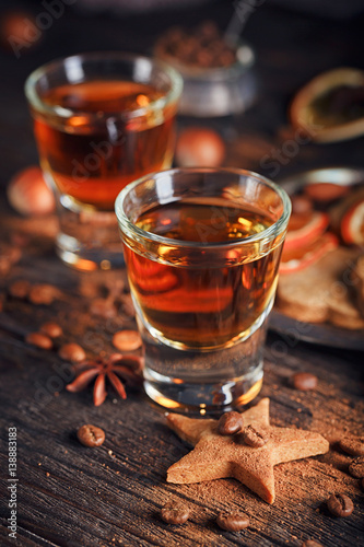 Whiskey or liqueur, cookies, spices and decorations on wooden background.