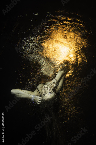unconscious girl levitats underwater with fire over the surface