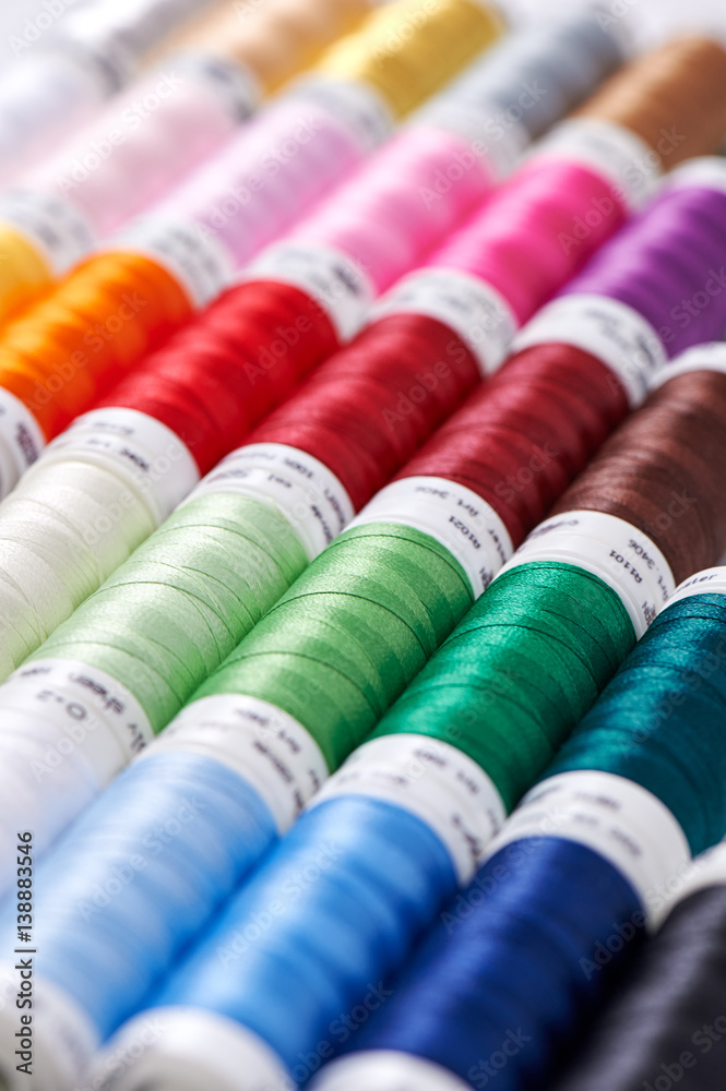 Background from spools with multicolored sewing threads Background from spools with multicolored sewing threads