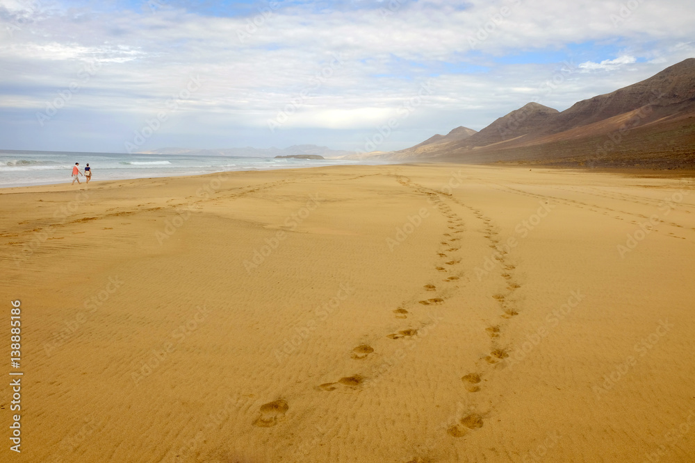 Beach Cofete and a couple walking along it on Fuerteventura, Spain. Beach Cofete and a couple walking along it on Fuerteventura, Spain.