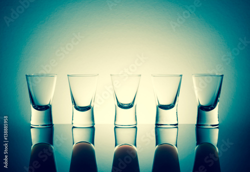 Small glasses with a drink shots of alcohol with reflection stainding in a table. photo