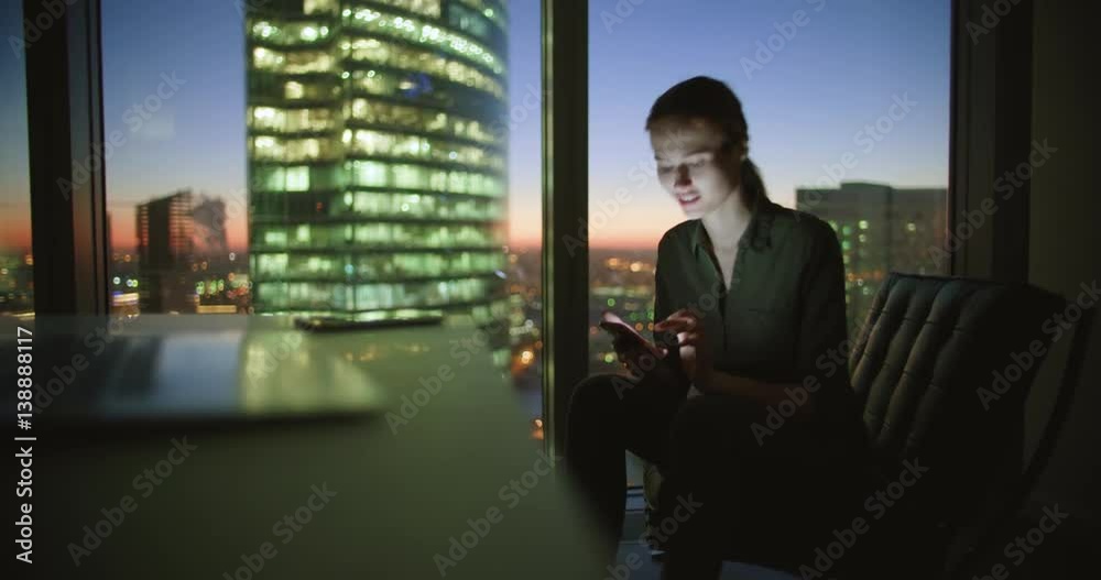 young girl in office in the evening sits at the table and wrote sms, dolly shot