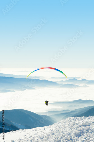 Paraglider in the sky above a snowy mountain top