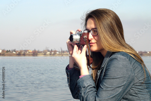 Photos Young woman adjusts vintage retro camera for photos
