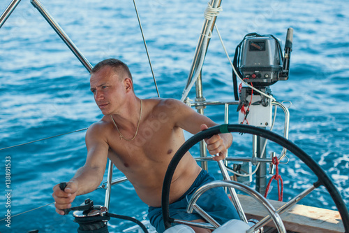 Skipper man at the helm controls of a sailing yacht during sea boats race. © De Visu
