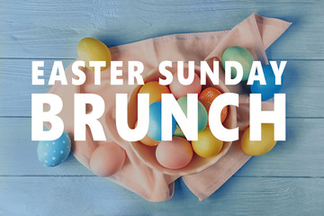 Bowl with colourful Easter eggs and napkin on blue wooden table