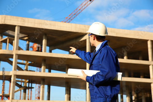 Young engineer pointing at unfinished building