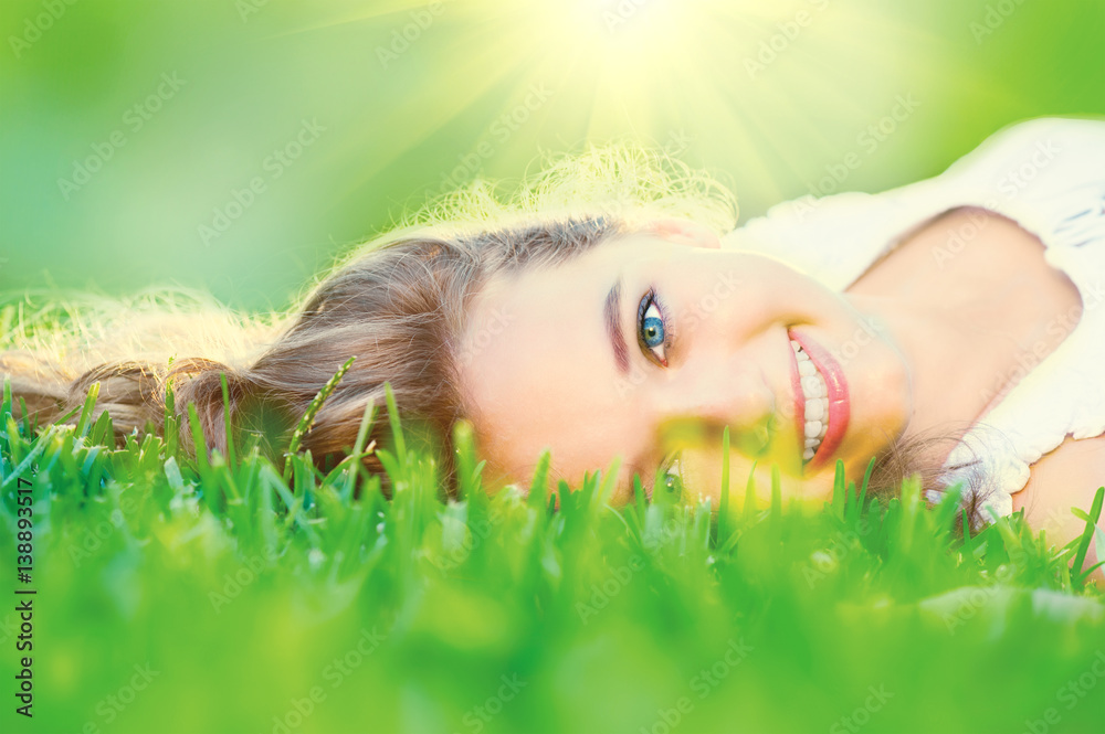 Beautiful teenage girl lying on green grass outdoor Beautiful teenage girl lying on green grass outdoor