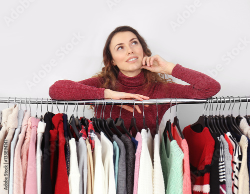 Beautiful young woman choosing clothes in modern shop