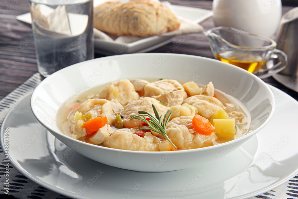 White plate of delicious chicken and dumplings on dining table White plate of delicious chicken and dumplings on dining table