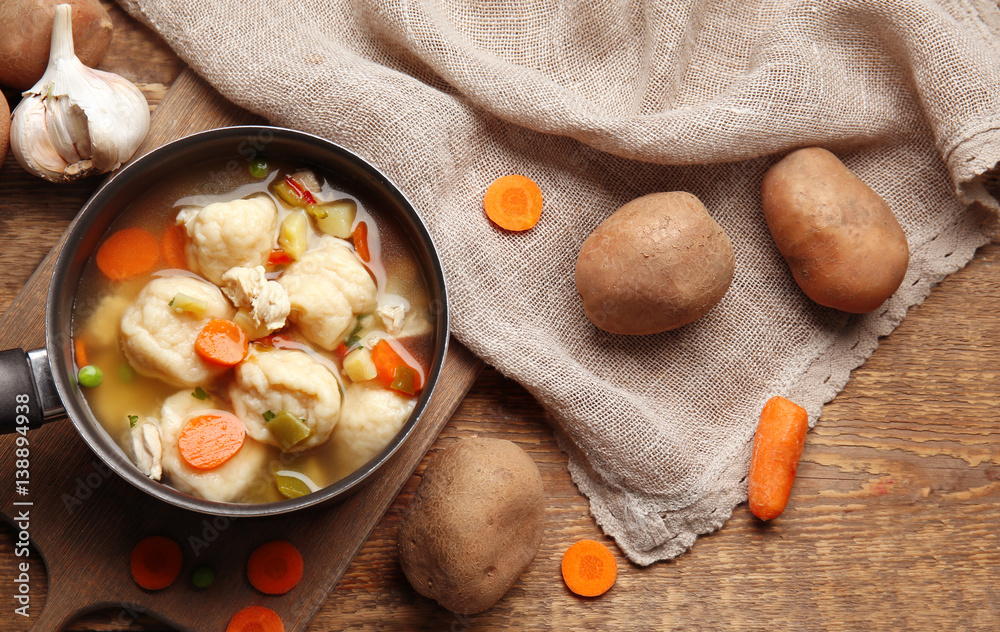 Stewpan with delicious chicken and dumplings on wooden background Stewpan with delicious chicken and dumplings on wooden background