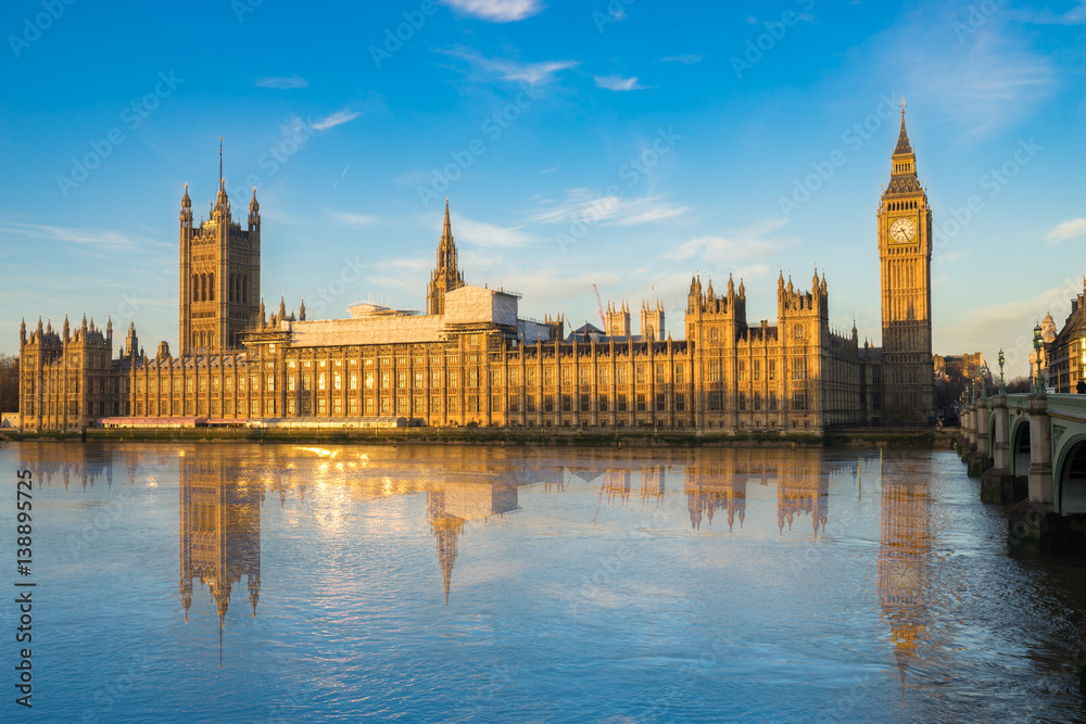 Big Ben and Westminster parliament with blue sky and water reflection in London, UK