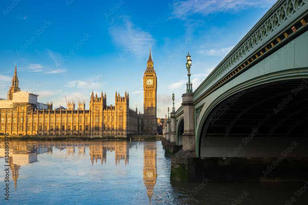 Big Ben and Westminster parliament with blue sky and water reflection in London, UK