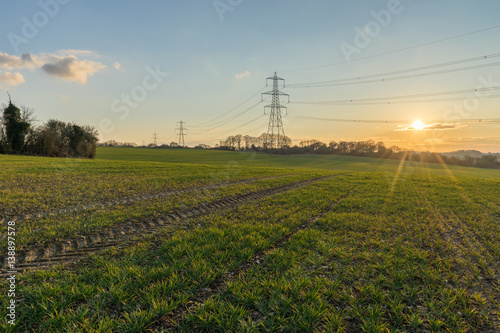 Meadow and Electricity Pylon - UK standard overhead power line transmission tower at sunset