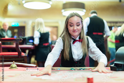 Cute lady casino dealer at poker table.