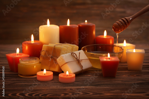 Beautiful composition of alight candles and honey treatments on wooden table