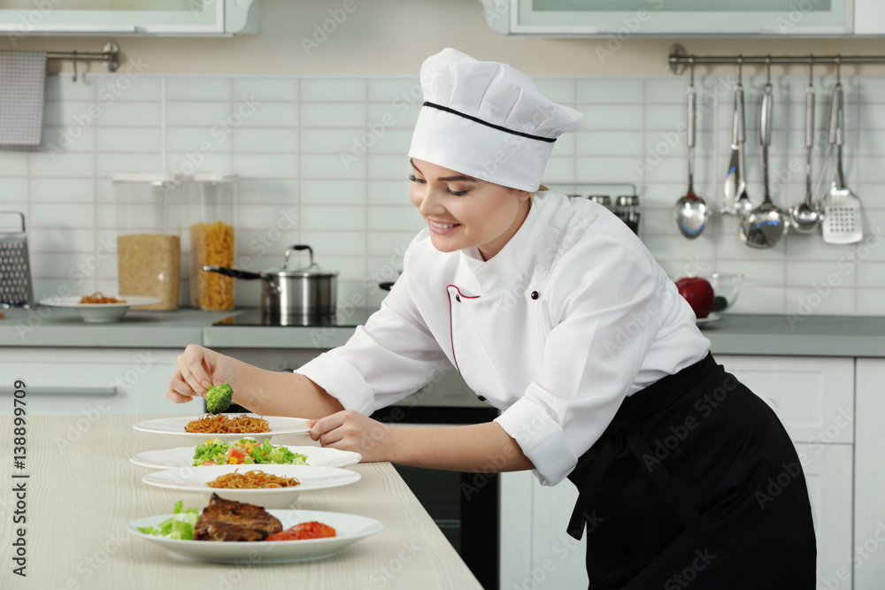 Young woman chef with different dishes on plates in modern kitchen Young woman chef with different dishes on plates in modern kitchen