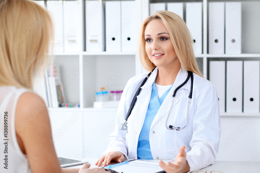 Doctor and patient discussing something while sitting at the table . Medicine and health care concept Doctor and patient discussing something while sitting at the table . Medicine and health care concept