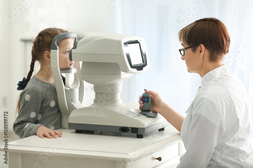 Ophthalmologist measuring intraocular pressure of little girl in clinic