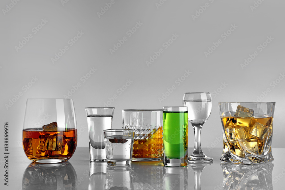 Glasses of wine and spirits on light background