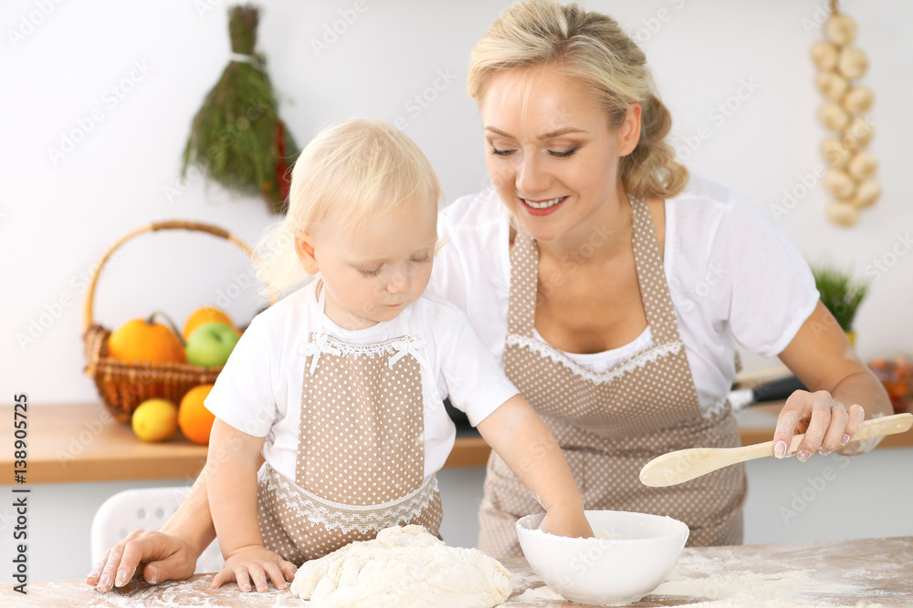 Happy family in the kitchen. Mother and child daughter cooking holiday pie or cookies for Mothers day, casual lifestyle photo series in real life interior Happy family in the kitchen. Mother and child daughter cooking holiday pie or cookies for Mothers day, casual lifestyle photo series in real life interior