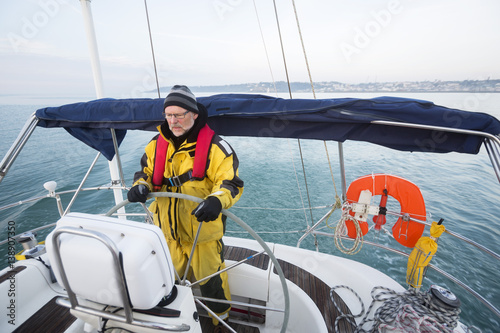Man Wearing Waterproof Jacket While Steering Yacht In Sea © Tyler Olson