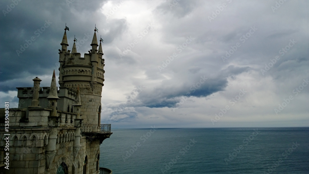 Famous landmark South of the Crimea - the Swallow's nest castle in cloudy weather. Calm Black sea and the beautiful clouds