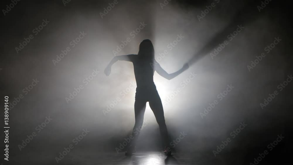 Leggy girl dancing in a smoky studio rhythmic dance. Silhouette Leggy girl dancing in a smoky studio rhythmic dance. Silhouette