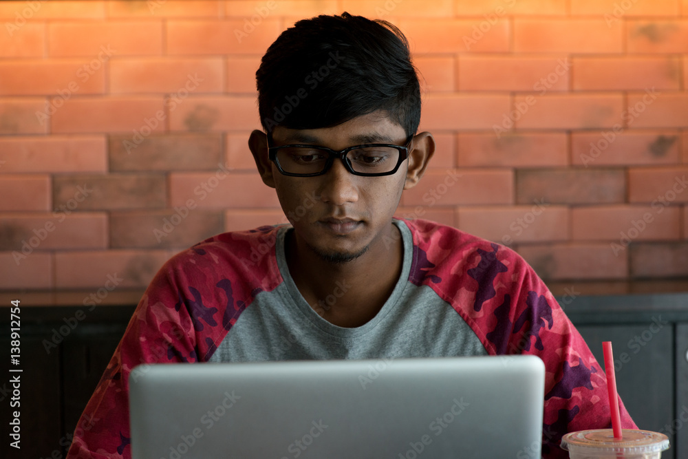 indian teenage male drinking coffee doing homework at cafe - obrazy, fototapety, plakaty 