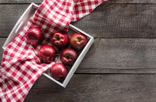 Ripe red apples in birch-box on wooden board with red checkered napkin around and copy space. photo