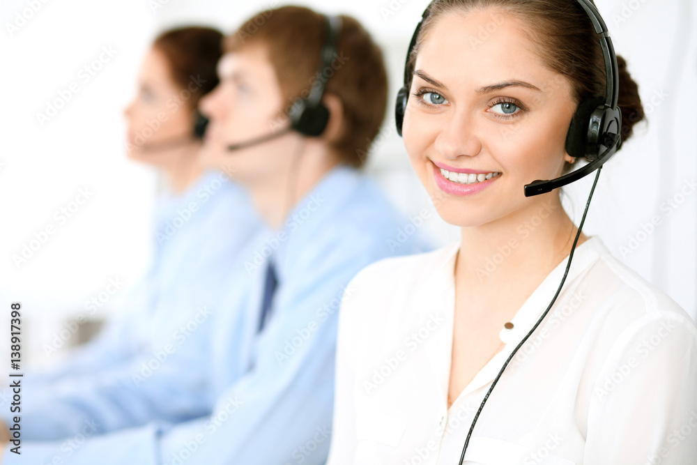 Call center operators. Focus at brunette business woman in headset Call center operators. Focus at brunette business woman in headset