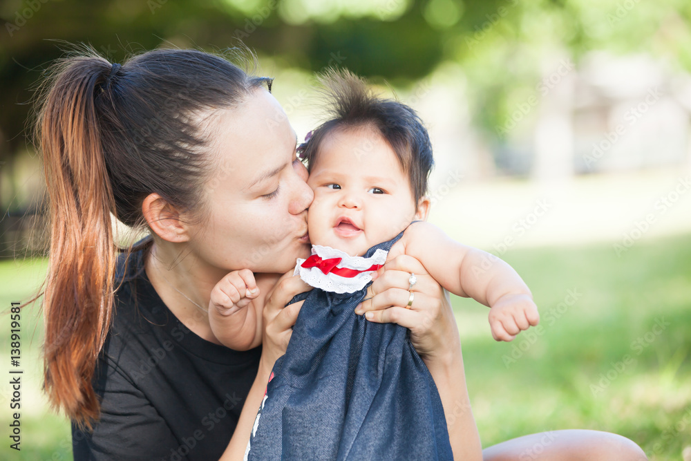 Young mother kisses her cute baby on the cheek Young mother kisses her cute baby on the cheek