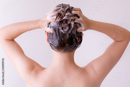Sexy model massaging shampoo into her hair, closeup profile from the back