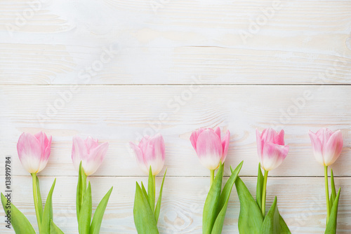 Fototapeta Naklejka Na Ścianę i Meble -  Row of tulips on wooden background with space for message. Mother's Day background. Top view