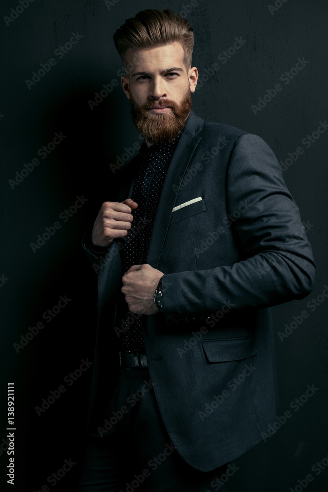 Stylish handsome bearded man in trendy suit posing on black Stylish handsome bearded man in trendy suit posing on black