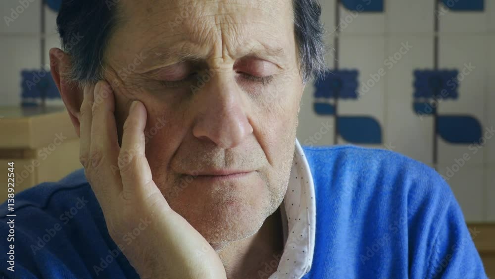 sad and pensive old man holding his face with his hand