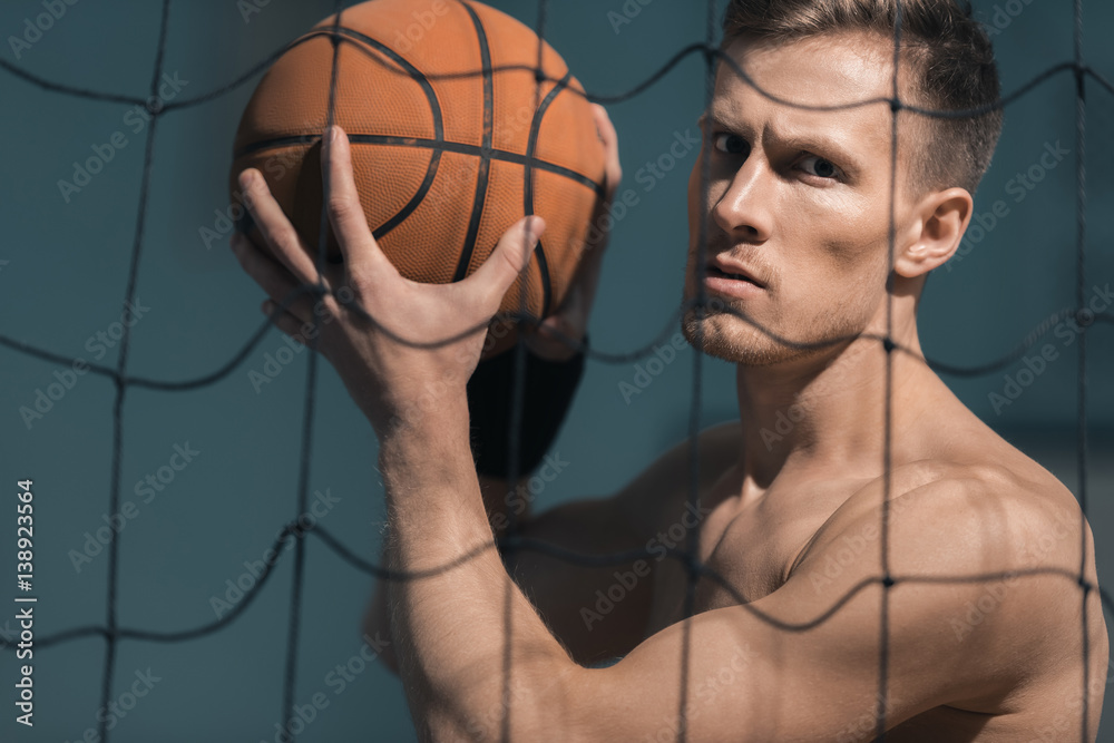 portrait of concentrated sporty man holding basketball ball in hands