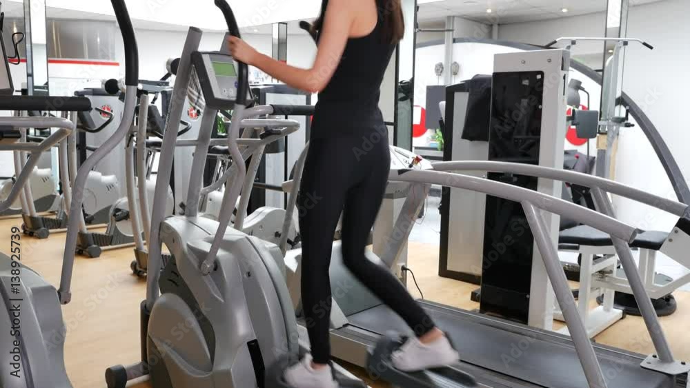 Woman exercises with elliptical cross trainer in sport fitness gym club Woman exercises with elliptical cross trainer in sport fitness gym club