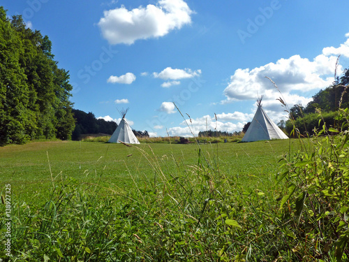 summer meadow with two tipis for camping