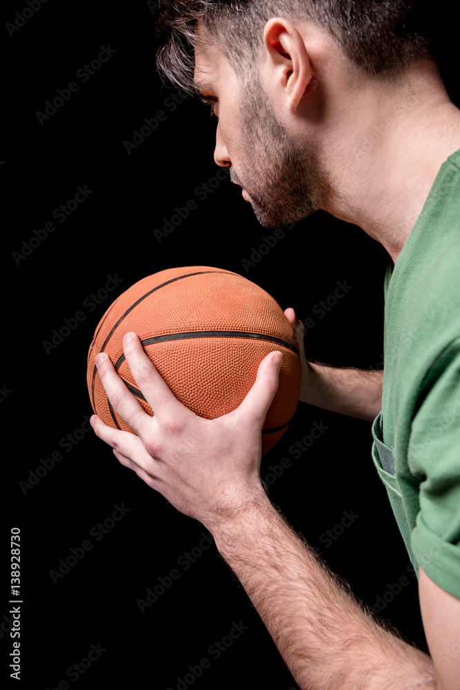 side view of concentrated man holding basketball ball on black side view of concentrated man holding basketball ball on black