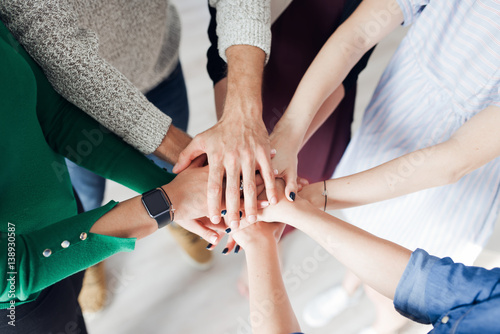 Obraz na płótnie Group of co-workers standing in a circle with their hands in a huddle