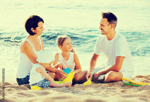 Parents with two kids playing with toys on beach