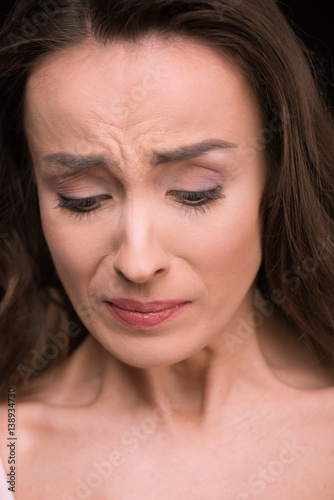 Close-up portrait of beautiful young woman crying and looking down