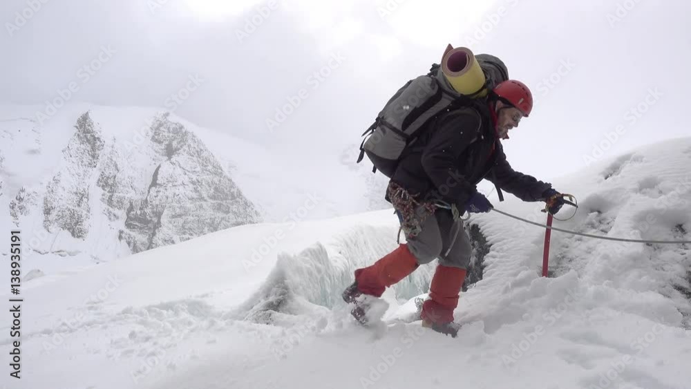 Mountain climber stepping over crevasse on mountain Mountain climber stepping over crevasse on mountain