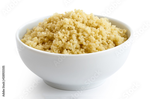 Cooked couscous in white ceramic bowl isolated on white.
